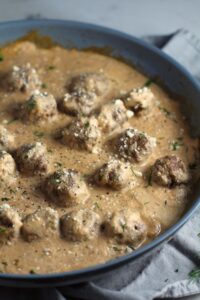 Meatballs in Cauliflower Dill Cream Sauce in a skillet. The Meatballs are swimming in a beautiful creamy cauliflower sauce flavored with garlic, fresh dill, cream cheese, and a touch of tomato paste. #meatballs #swedishmeatballs #familydinner #easydinner #dinner #healthydinner