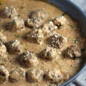 Dill Meatballs in Cauliflower Dill Cream Sauce in a skillet. The Meatballs are swimming in a beautiful creamy cauliflower sauce flavored with garlic, fresh dill, cream cheese, and a touch of tomato paste. #meatballs #swedishmeatballs #familydinner #easydinner #dinner #healthydinner