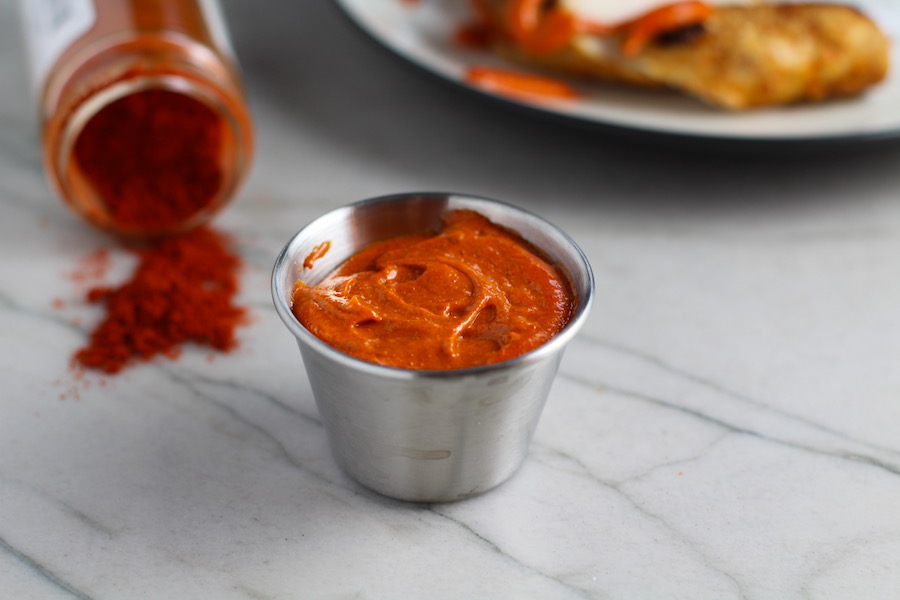 Hungarian Paprika Aioli in silver cup with Paprika spilling out of jar on counter for Hungarian Paprika Chicken. The paprika gives beautiful color and a deep, peppery flavor. #chicken #easychicken #easydinner #dinner #healthydinner