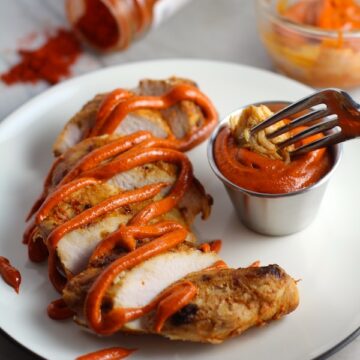 Hungarian Paprika Chicken sliced on plate with Paprika Aioli drizzled on top and fork dipping a bite. The paprika gives beautiful color and a deep, peppery flavor. #chicken #easychicken #easydinner #dinner #healthydinner