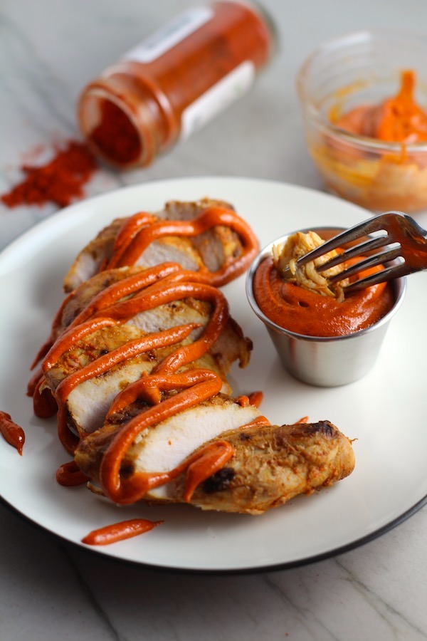 Hungarian Paprika Chicken sliced on plate with Paprika Aioli drizzled on top and fork dipping a bite. The paprika gives beautiful color and a deep, peppery flavor. #chicken #easychicken #easydinner #dinner #healthydinner