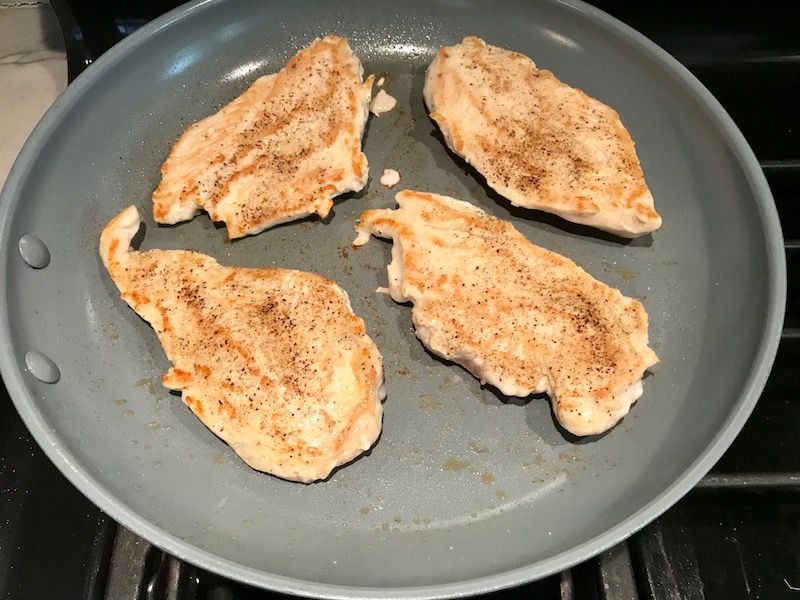 Chicken cooking in pan for Lemon Dill Sauce Chicken and Asparagus. It has chicken in a light and creamy sauce flavored with garlic, lemon and fresh dill. It's loaded with fresh asparagus. #springrecipes #dinner #easydinner #healthydinner #lemon #asparagus #chicken #glutenfree #easyrecipes