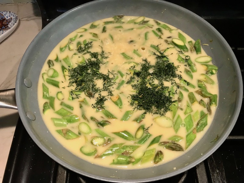 Dill added to cut asparagus and sauce cooking in pan for Lemon Dill Sauce Chicken and Asparagus. It has chicken in a light and creamy sauce flavored with garlic, lemon and fresh dill. It's loaded with fresh asparagus. #springrecipes #dinner #easydinner #healthydinner #lemon #asparagus #chicken #glutenfree #easyrecipes
