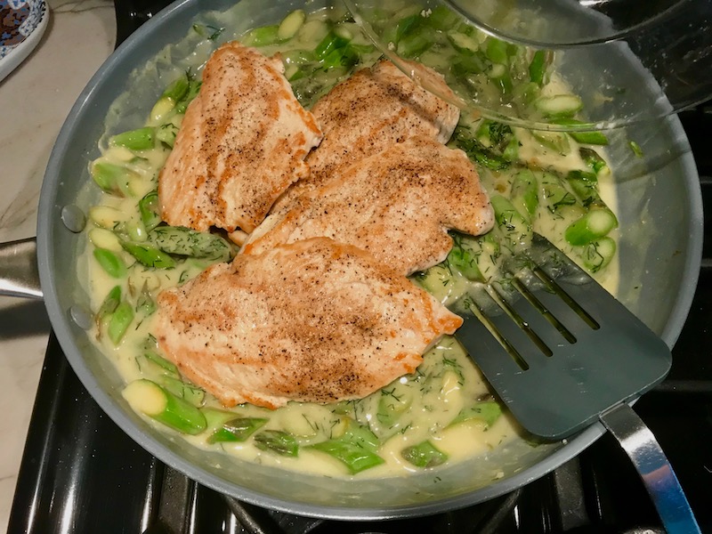 Chicken added to asparagus sauce in pan for Lemon Dill Sauce Chicken and Asparagus. It has chicken in a light and creamy sauce flavored with garlic, lemon and fresh dill. It's loaded with fresh asparagus. #springrecipes #dinner #easydinner #healthydinner #lemon #asparagus #chicken #glutenfree #easyrecipes