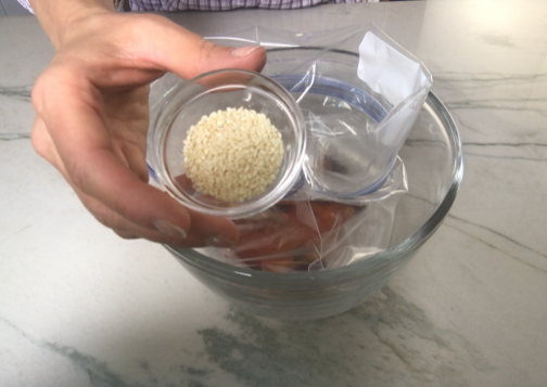 Sesame Seeds about to be poured into a storage bag propped up in a bowl for Sesame Sweet Chili Chicken recipe. It is slightly sweet, tangy, savory, nutty, with a touch of heat. You can prepare it days ahead, it takes just minutes to prepare, minutes to cook, and everyone will love it!! #chicken #marinades #easydinner #easychicken #chickenrecipes #easysauces #healthydinner #healthyfood #healthyrecipes