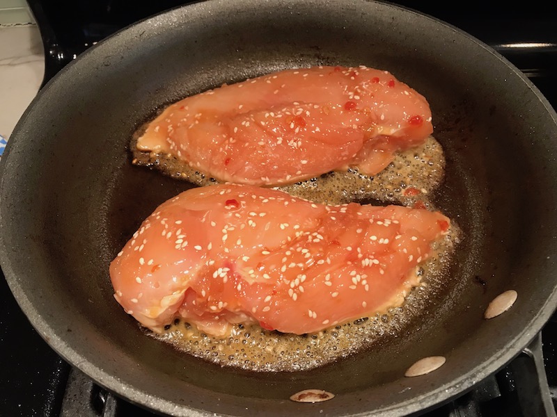 Raw Chicken getting seared in skillet for Sesame Sweet Chili Chicken recipe. It is slightly sweet, tangy, savory, nutty, with a touch of heat. You can prepare it days ahead, it takes just minutes to prepare, minutes to cook, and everyone will love it!! #chicken #marinades #easydinner #easychicken #chickenrecipes #easysauces #healthydinner #healthyfood #healthyrecipes