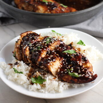 Sesame Sweet Chili Chicken cooked and sliced on a plate with rice and cilantro. It is slightly sweet, tangy, savory, nutty, with a touch of heat. You can prepare it days ahead, it takes just minutes to prepare, minutes to cook, and everyone will love it!! #chicken #marinades #easydinner #easychicken #chickenrecipes #easysauces #healthydinner #healthyfood #healthyrecipes
