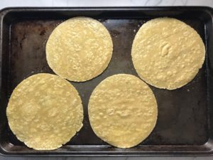 4 corn tortillas on sheet pan for Skillet Eggs in Spicy Tomato Pepper Sauce with Manchego Cheese. With a smoky, spicy, thick, and luscious red pepper tomato sauce. #eggs #huevosrancheros #tomatosauce #easydinner #brunch #shakshuka
