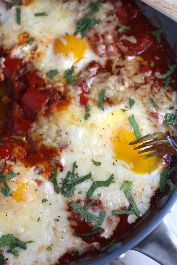 Skillet Eggs in Spicy Tomato Pepper Sauce with Manchego Cheese cooked in a skillet. With a smoky, spicy, thick, and luscious red pepper tomato sauce. #eggs #huevosrancheros #tomatosauce #easydinner #brunch #shakshuka