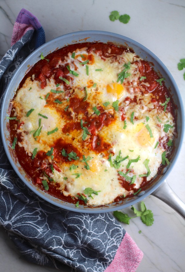 Skillet Eggs in Spicy Tomato Pepper Sauce with Manchego Cheese cooked in a skillet. With a smoky, spicy, thick, and luscious red pepper tomato sauce. #eggs #huevosrancheros #tomatosauce #easydinner #brunch #shakshuka