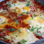Skillet Eggs in Spicy Tomato Pepper Sauce with Manchego Cheese cooked in a skillet. With a smoky, spicy, thick, and luscious red pepper tomato sauce. #eggs #huevosrancheros #tomatosauce #easydinner #brunch #shakshuka