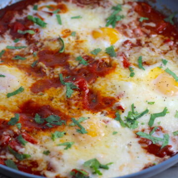 Skillet Eggs in Spicy Tomato Pepper Sauce with Manchego Cheese cooked in a skillet. With a smoky, spicy, thick, and luscious red pepper tomato sauce. #eggs #huevosrancheros #tomatosauce #easydinner #brunch #shakshuka