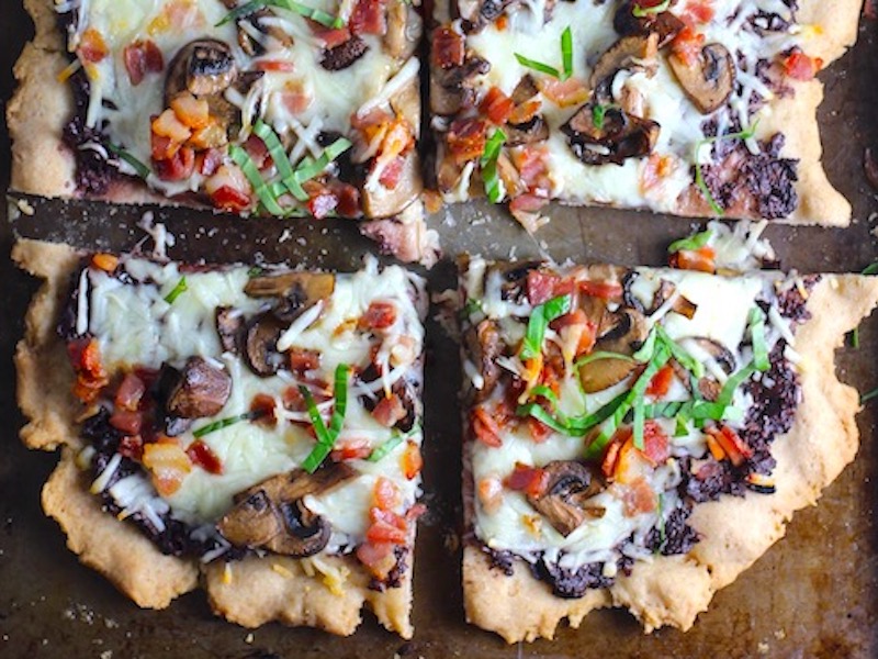 Flatbread cut into 4 pieces on a pan with a crispy gluten free crust, salty and briny Olive Tapenade, creamy mozzarella, earthy and meaty mushrooms, peppery pancetta, and fresh basil. #flatbread #pizza #olives #tapenade #mediterranean #easydinner #dinner