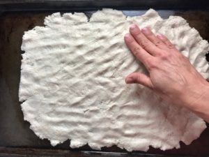 Hand pressing Flatbread dough out in a pan for Olive & Pancetta Flatbread with mozzarella, mushrooms, and fresh basil. #flatbread #pizza #olives #tapenade #mediterranean #easydinner #dinner