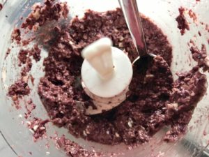 Olive tapenade in food processor with spoon for Olive & Pancetta Flatbread with mozzarella, mushrooms, and fresh basil. #flatbread #pizza #olives #tapenade #mediterranean #easydinner #dinner