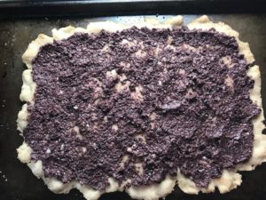 Olive tapenade spread on flatbread for Olive & Pancetta Flatbread with mozzarella, mushrooms, and fresh basil. #flatbread #pizza #olives #tapenade #mediterranean #easydinner #dinner