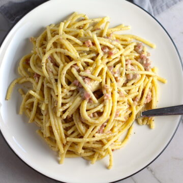 Pancetta, Parmesan, and Pepper Pasta on plate with fork. The Pancetta gives a salty and slightly peppery flavor, Parmesan cheese creates a nutty and creamy sauce, and the ground black pepper gives a peppery flavor that makes this pasta stand out. #pasta #easypasta #easydinner #dinner #italian #familydinner #onpotdinners #onepandinners #parmesan