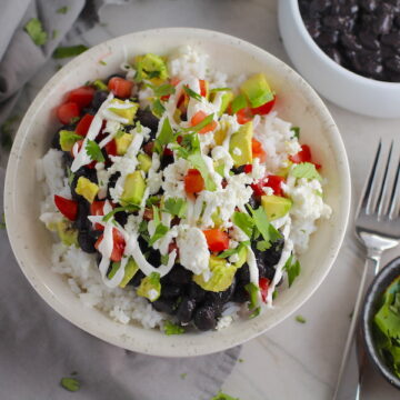 Black Bean Taco Bowl with rice, smoky black beans, avocado, salty Cotija cheese, sour cream, fresh tomato, and bright cilantro. This Black Bean Taco Bowl Bar lets everyone fills their bowl with any of the toppings they want! Perfect for kids. #tacos #tacobowls #healthyfood #dinner #healthydinner #familydinner #kidsdinner #blackbeans #vegetarian