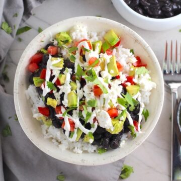Black Bean Taco Bowl with rice, smoky black beans, avocado, salty Cotija cheese, sour cream, fresh tomato, and bright cilantro. This Black Bean Taco Bowl Bar lets everyone fills their bowl with any of the toppings they want! Perfect for kids.
