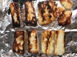 Grilled Halloumi on pan Grilled Halloumi Cheese & Tomato Salad. It's insanely delicious! Grilled Halloumi has a strong savory and salty flavor that is slightly creamy and incredibly addictive. Paired with my simple Tomato and Basil salad, each bite is simply heaven. #halloumi #appetizers #salads #grilling #summerfood