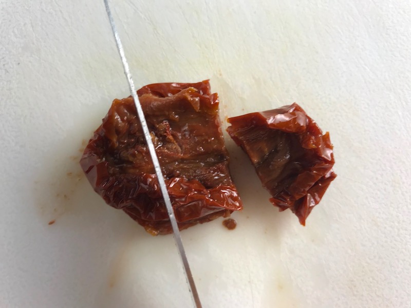 Knife cutting sun dried tomatoes for Skillet Artichoke Chicken with sun dried tomatoes, basil, garlic, in cream sauce. #skilletchicken #skilletdinner #chicken #easydinner #familydinner #italian #tuscanchicken