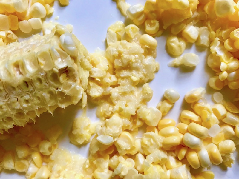 Kernels cut from a cob of corn for Gluten Free Corn Chowder with Turmeric. Scallions on top for garnish. It's thick, creamy, silky and delicious. The entire family will love this easy stovetop corn soup! #summerfood #cornsoup #corn #vegetarian #vegetablerecipes #sides