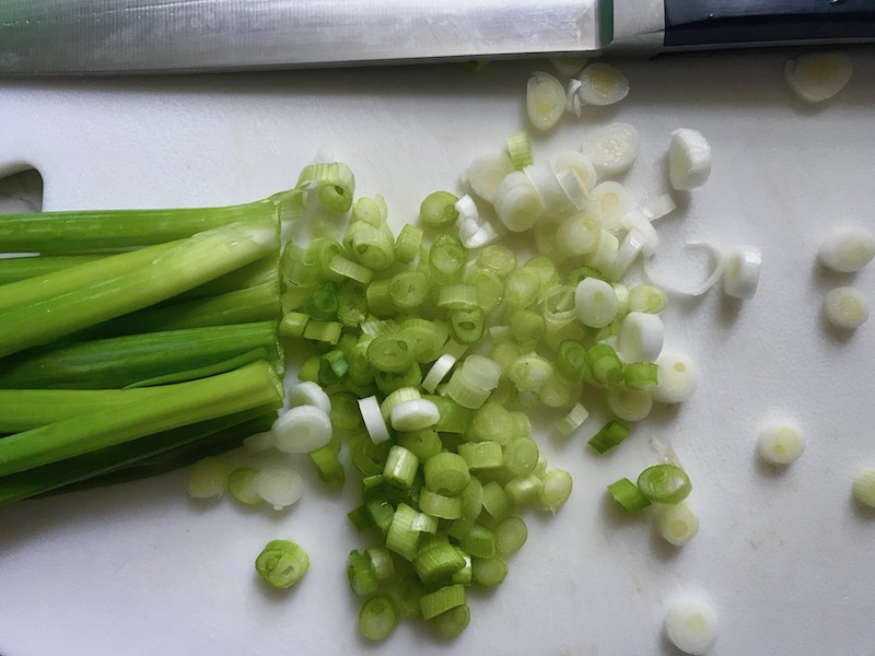 Sliced scallions for Chilled Golden Corn Soup with Turmeric. Scallions on top for garnish. It's thick, creamy, silky and delicious. The entire family will love this easy stovetop corn soup! #summerfood #cornsoup #corn #vegetarian #vegetablerecipes #sides