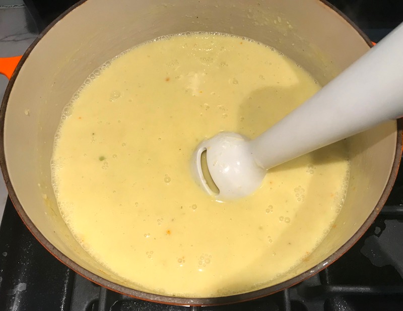 Immersion blender blending corn soup in pot for Gluten Free Corn Chowder with Turmeric. Scallions on top for garnish. It's thick, creamy, silky and delicious. The entire family will love this easy stovetop corn soup! #summerfood #cornsoup #corn #vegetarian #vegetablerecipes #sides
