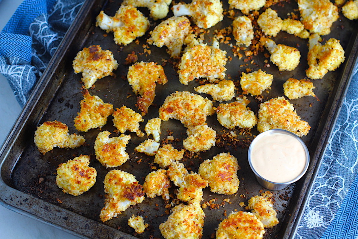 Breaded Cauliflower Recipe on pan. They have a slightly sweet and salty crunch outside from the shredded coconut and panko mixture. The inside is soft and creamy.