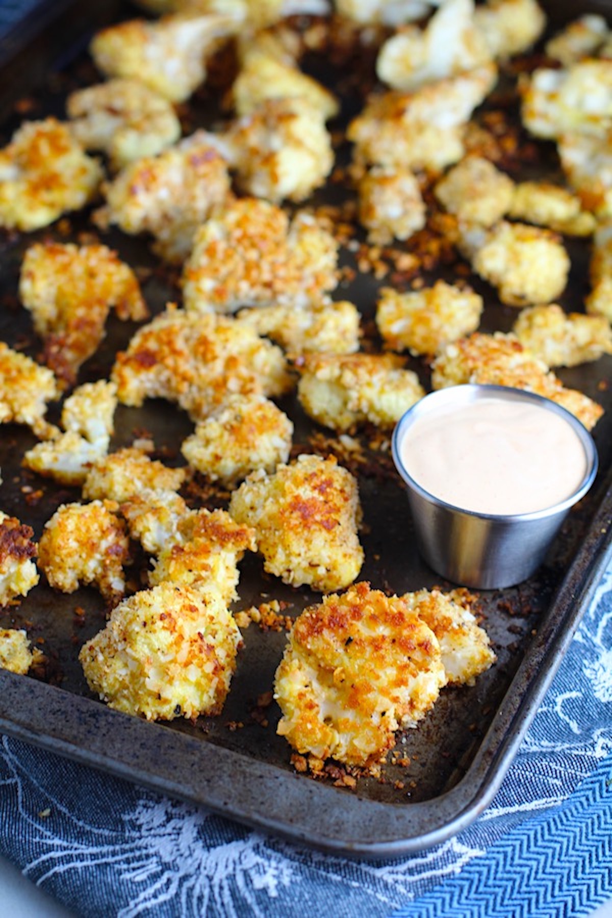 BReaded Cauliflower Recipe on pan. They have a slightly sweet and salty crunch outside from the shredded coconut and panko mixture. The inside is soft and creamy.