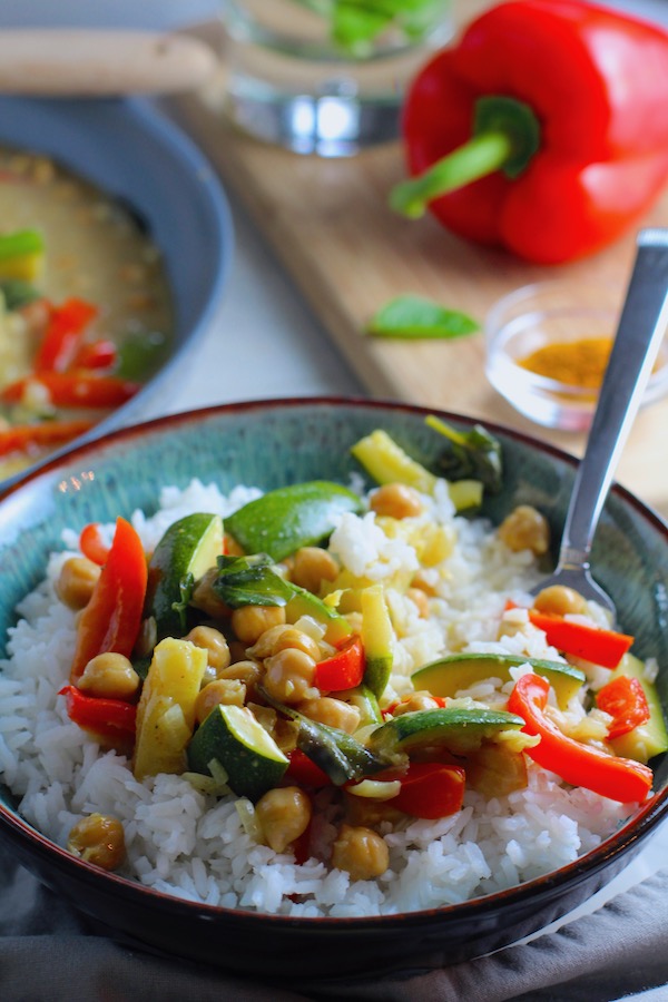 Family Chickpea Coconut Curry over rice in a bowl with red bell pepper, zucchini, onion, coconut milk, and warm Indian Curry spices.