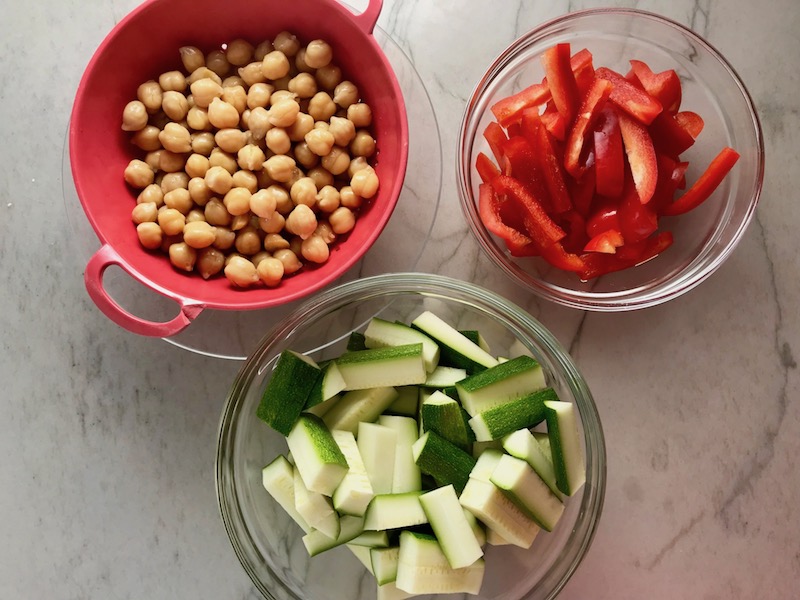 Chickpeas, sliced red pepper, and sliced zucchini for Chickpea Coconut Curry. The sauce has onion, coconut milk, ginger, garlic, and warm Indian Curry spices.