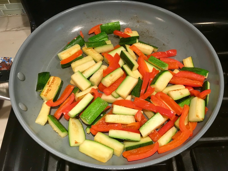 Red Peppers and Zucchini in pan for Family Coconut Curry. The sauce has onion, coconut milk, ginger, garlic, and warm Indian Curry spices.