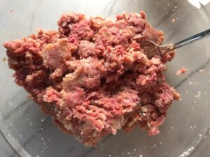 Mixed meat ingredients in bowl for Mini Meatloaf Muffins. They have only 5 simple ingredients, cook in 30 minutes, and are gluten free.