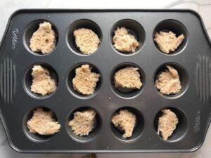 Bread in bottom of muffin tin slots for Mini Meatloaf Muffins. They have only 5 simple ingredients, cook in 30 minutes, and are gluten free.