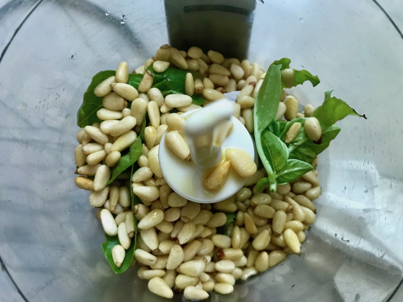 Basil, Pine nuts, garlic in mini food processor for Broccoli Pesto Pasta. It's delicious AND good for you! It has all of the classic pesto flavors from garlic, basil, parmesan cheese, and pine nuts. But the flavor is a bit more mellow by adding broccoli! #broccolirecipes #pesto #pasta #easydinner #dinnerideas #familydinner