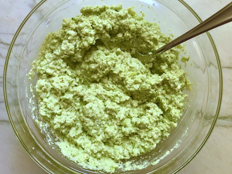 Broccoli Pesto in a bowl with spoon. It's delicious AND good for you! It has all of the classic pesto flavors from garlic, basil, parmesan cheese, and pine nuts. But the flavor is a bit more mellow by adding broccoli! #broccolirecipes #pesto #pasta #easydinner #dinnerideas #familydinner