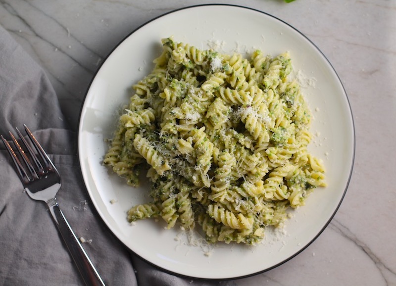 Broccoli Pesto Pasta on a plate with parmesan on top. It's delicious AND good for you! It has all of the classic pesto flavors from garlic, basil, parmesan cheese, and pine nuts. But the flavor is a bit more mellow by adding broccoli! #broccolirecipes #pesto #pasta #easydinner #dinnerideas #familydinner