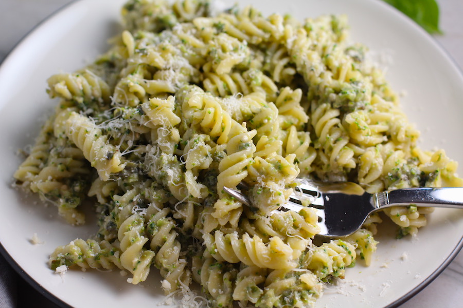 Broccoli Pesto Pasta on a plate with fork in pasta. It's delicious AND good for you! It has all of the classic pesto flavors from garlic, basil, parmesan cheese, and pine nuts. But the flavor is a bit more mellow by adding broccoli! #broccolirecipes #pesto #pasta #easydinner #dinnerideas #familydinner