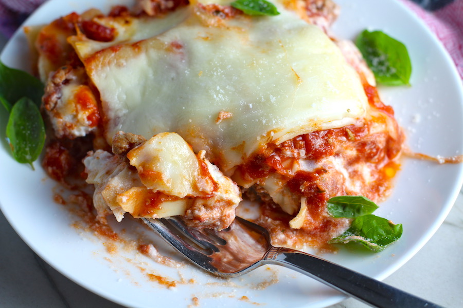 Lasagne on a plate with a fork cutting bite. from the dish. This Italian Sausage Lasagne Recipe is the stuff that dreams are made of. Layers of pasta, creamy ricotta, salty chewy mozzarella, salty and hearty Italian Sausage, and sweet and tangy tomato sauce.