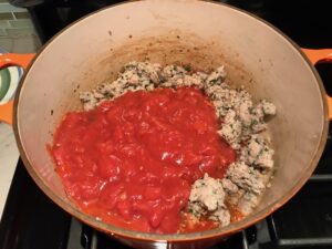 Homemade Italian Sausage and tomatoes in pot for this Easy Italian Sausage Chicken Lasagna Recipe. It's the stuff that dreams are made of. Layers of pasta, creamy ricotta, salty chewy mozzarella, salty and hearty Italian Sausage, and sweet and tangy tomato sauce.