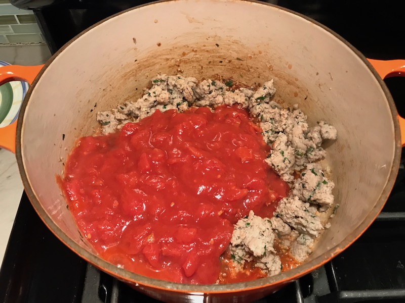 Homemade Italian Sausage and tomatoes in pot for this Easy Italian Sausage Lasagne Recipe. It's the stuff that dreams are made of. Layers of pasta, creamy ricotta, salty chewy mozzarella, salty and hearty Italian Sausage, and sweet and tangy tomato sauce.