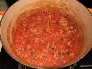 Homemade Italian Sausage Tomato Sauce in pot for this Easy Italian Sausage Chicken Lasagna Recipe. It's the stuff that dreams are made of. Layers of pasta, creamy ricotta, salty chewy mozzarella, salty and hearty Italian Sausage, and sweet and tangy tomato sauce.