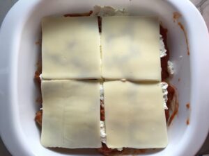 Layer of mozzarella over ricotta in dish for this Easy Italian Sausage chicken Lasagna Recipe. It's the stuff that dreams are made of. Layers of pasta, creamy ricotta, salty chewy mozzarella, salty and hearty Italian Sausage, and sweet and tangy tomato sauce.