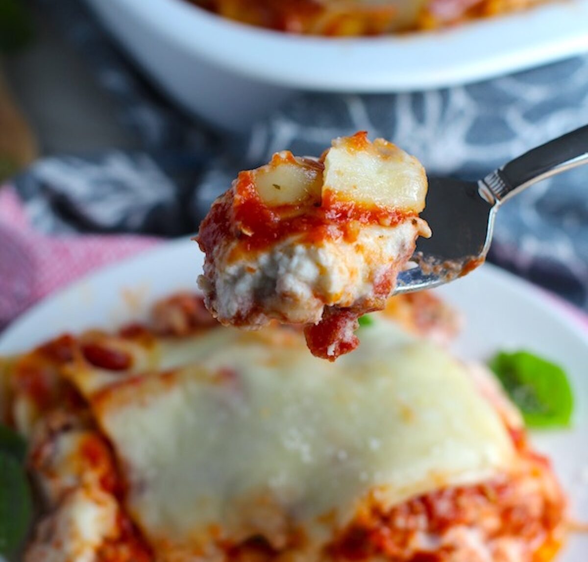 Chicken Lasagna on a plate with fork holding bite up. from the dish. This Easy ITalian Sausage Lasagne Recipe is the stuff that dreams are made of. Layers of pasta, creamy ricotta, salty chewy mozzarella, salty and hearty Italian Sausage, and sweet and tangy tomato sauce.