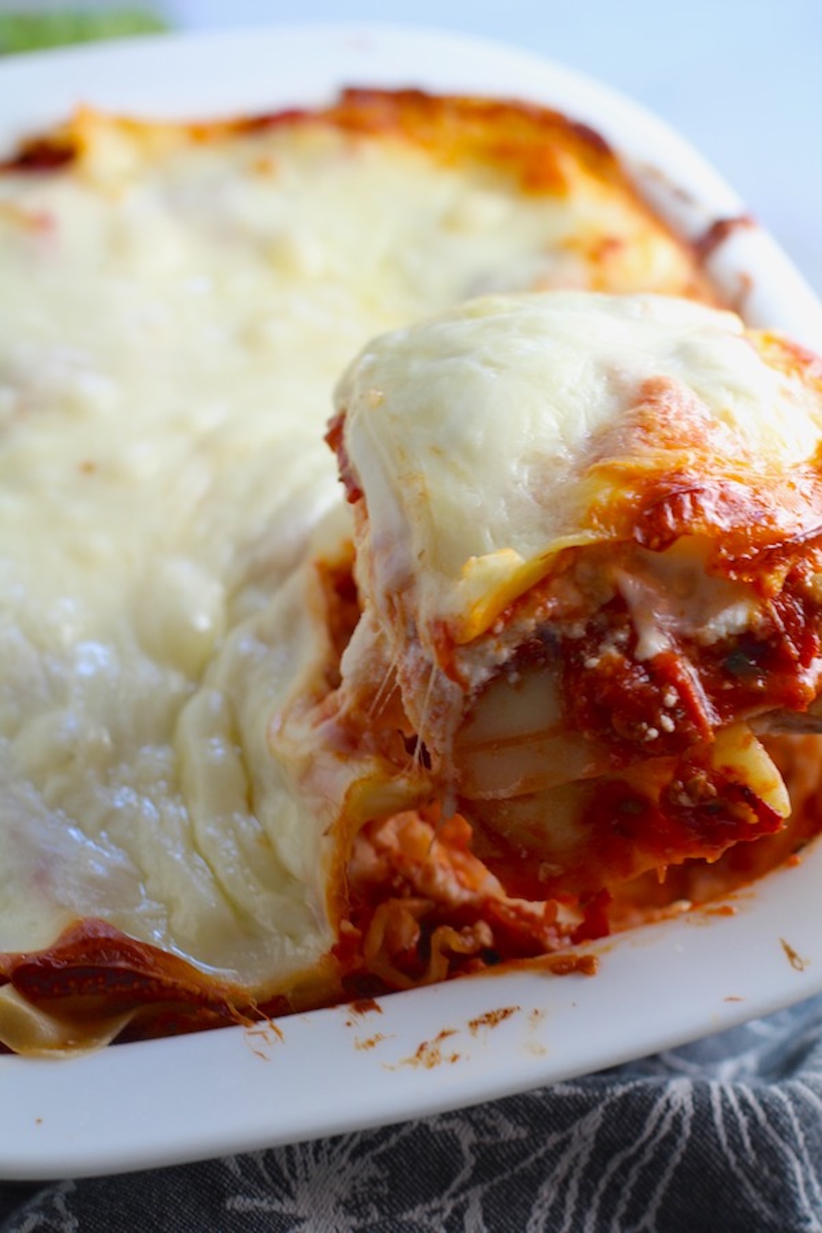 Scooping a piece of Chicken lasagna from the dish. This Lasagna with Ground Chicken Italian Sausage is the stuff that dreams are made of. Layers of pasta, creamy ricotta, salty chewy mozzarella, salty and hearty Italian Sausage, and sweet and tangy tomato sauce.