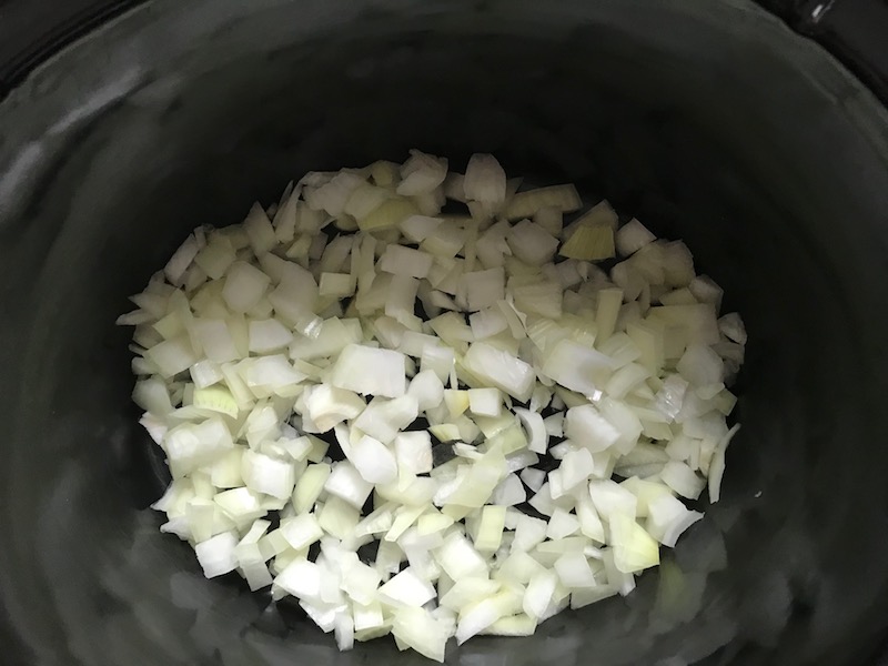 Diced onion in Slow Cooker insert for Smoky Pulled Beef Brisket. It's smokey, savory, tender, moist, and full of flavor. In a delicious sauce, it goes great on a sandwich, over polenta, on rice, or potatoes. #slowcooker #crockpot #brisket #beefbrisket #pulledbeef #pulledpork
