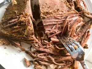 Fork shredding cooked brisket for Smoky Pulled Beef Brisket. It's smokey, savory, tender, moist, and full of flavor. In a delicious sauce, it goes great on a sandwich, over polenta, on rice, or potatoes. #slowcooker #crockpot #brisket #beefbrisket #pulledbeef #pulledpork
