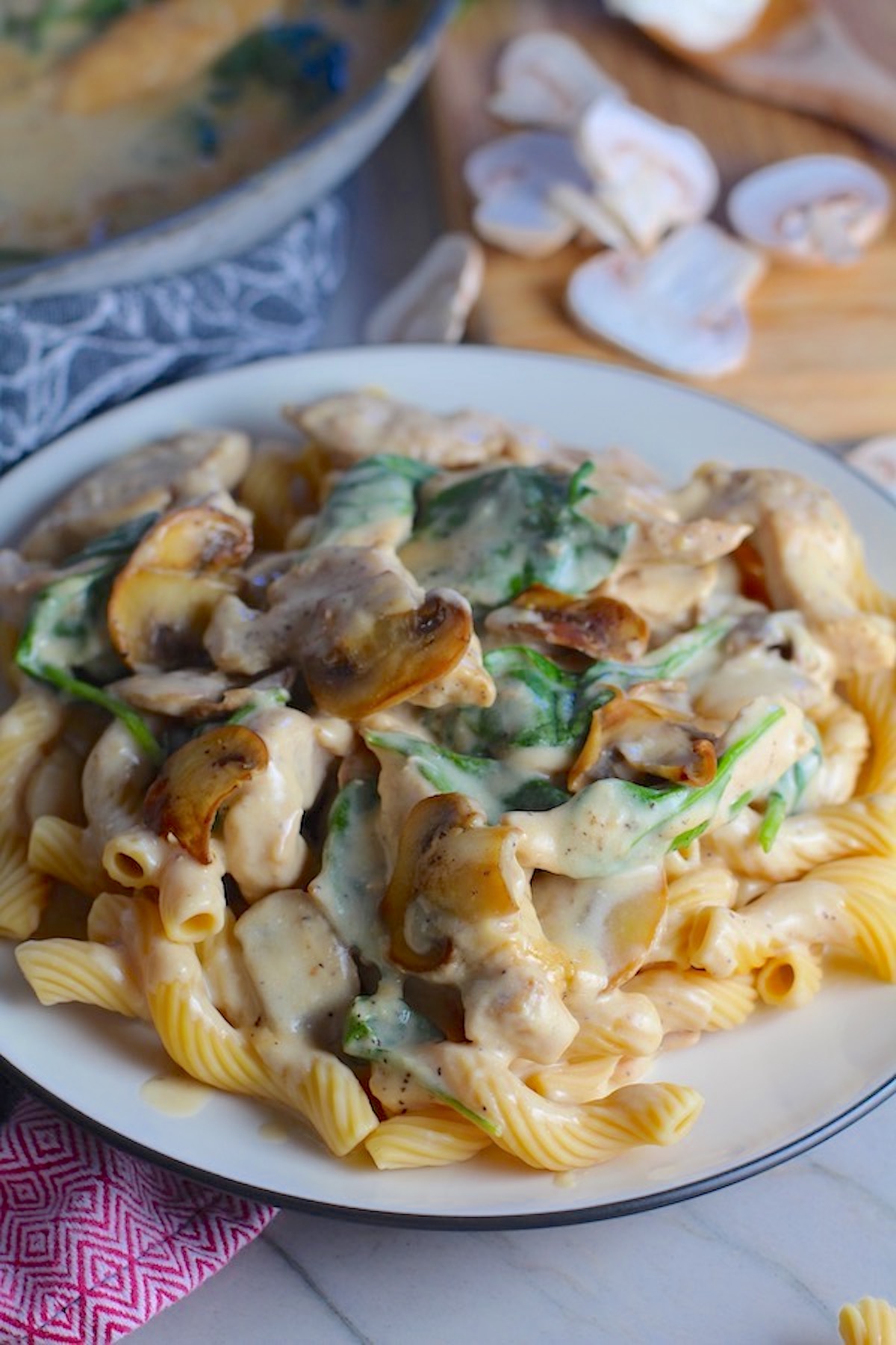 Chicken Mushroom Stroganoff on a plate with Cavatappi pasta, mushrooms, and spinach. It has a thick, creamy, savory mushroom sauce with a touch of tangy sour cream.