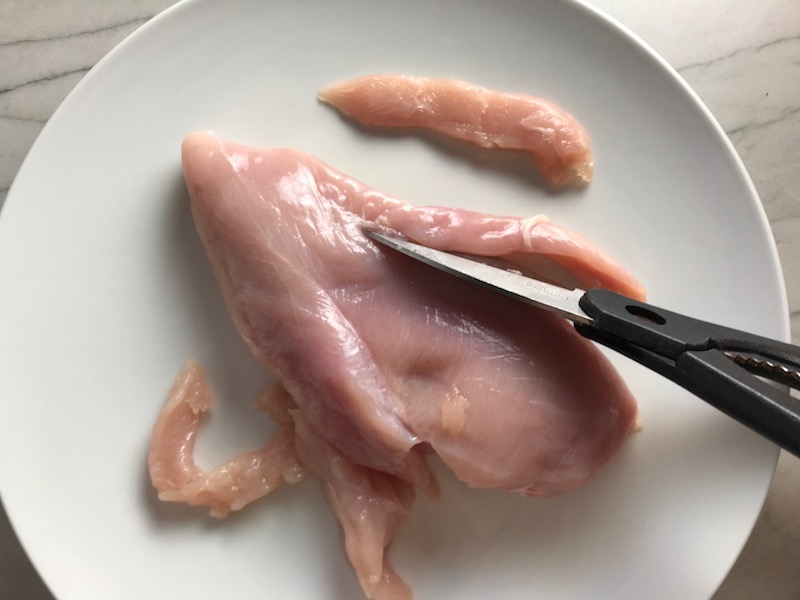 Cutting raw chicken for Chicken Mushroom Stroganoff with spinach. It has a thick, creamy, savory mushroom sauce with a touch of tangy sour cream. #chickendinners #chickenrecipes #familydinners #dinnerideas